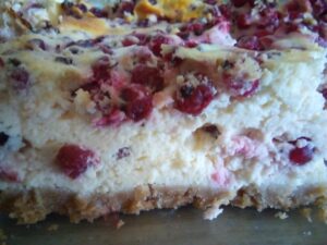 Slice of red currant cheesecake on a rustic plate.