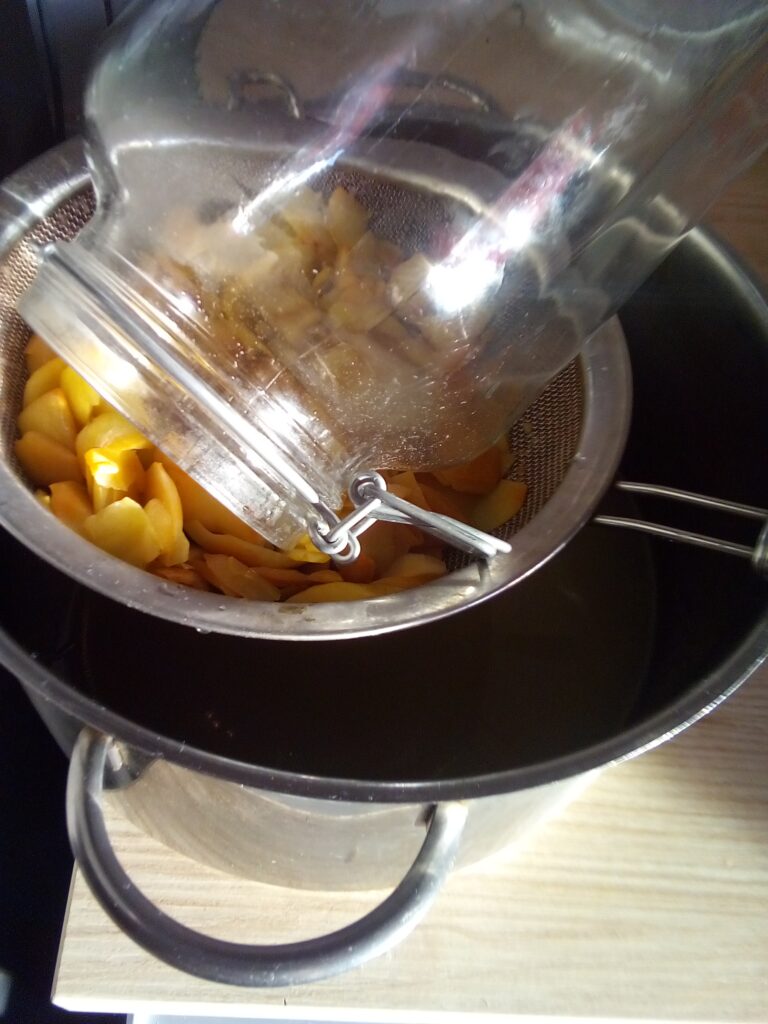 Straining fermented apple pieces from liquid to continue vinegar making