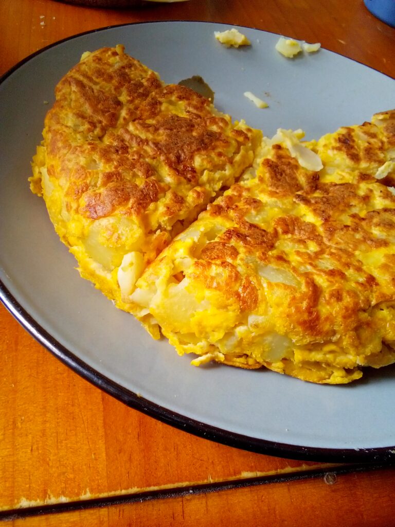 Spanish tortilla sliced into wedges, showing golden potatoes and fluffy eggs – a Spanish food classic.