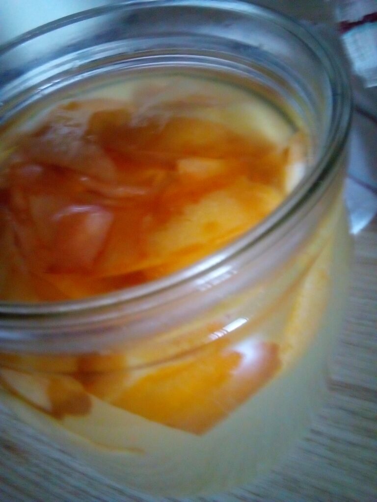 Golden homemade apple cider vinegar glowing in sunlight