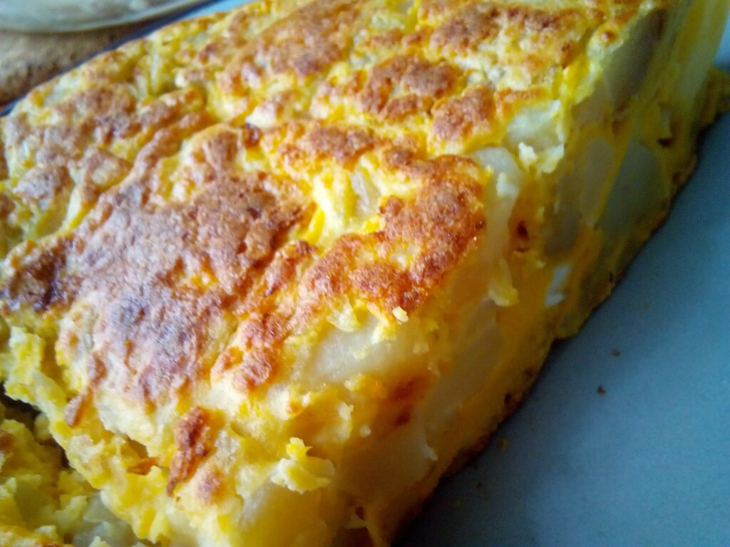 Authentic Spanish tortilla recipe cooked in a non-stick skillet – traditional Spanish food with potatoes and eggs.