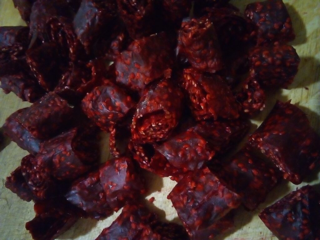 Maple syrup being drizzled into a bowl of berry puree for fruit leather.