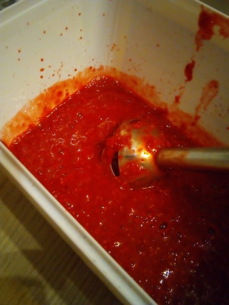 Raspberry puree in a glass bowl prepared without added sugar for fruit leather.