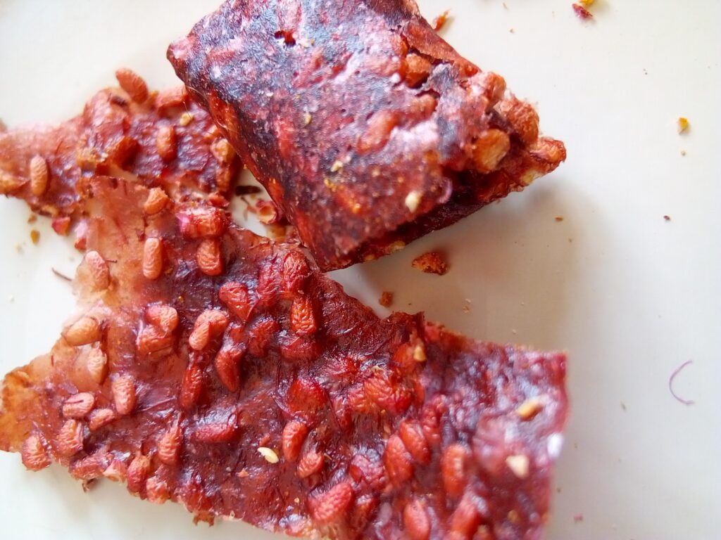 : Thin raspberry fruit leather rolls stored long term in a sealed glass jar.