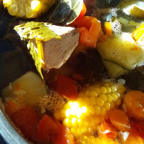Beef soup slowly simmering in a large pot with bones and vegetables using traditional homestead cooking methods and low heat.