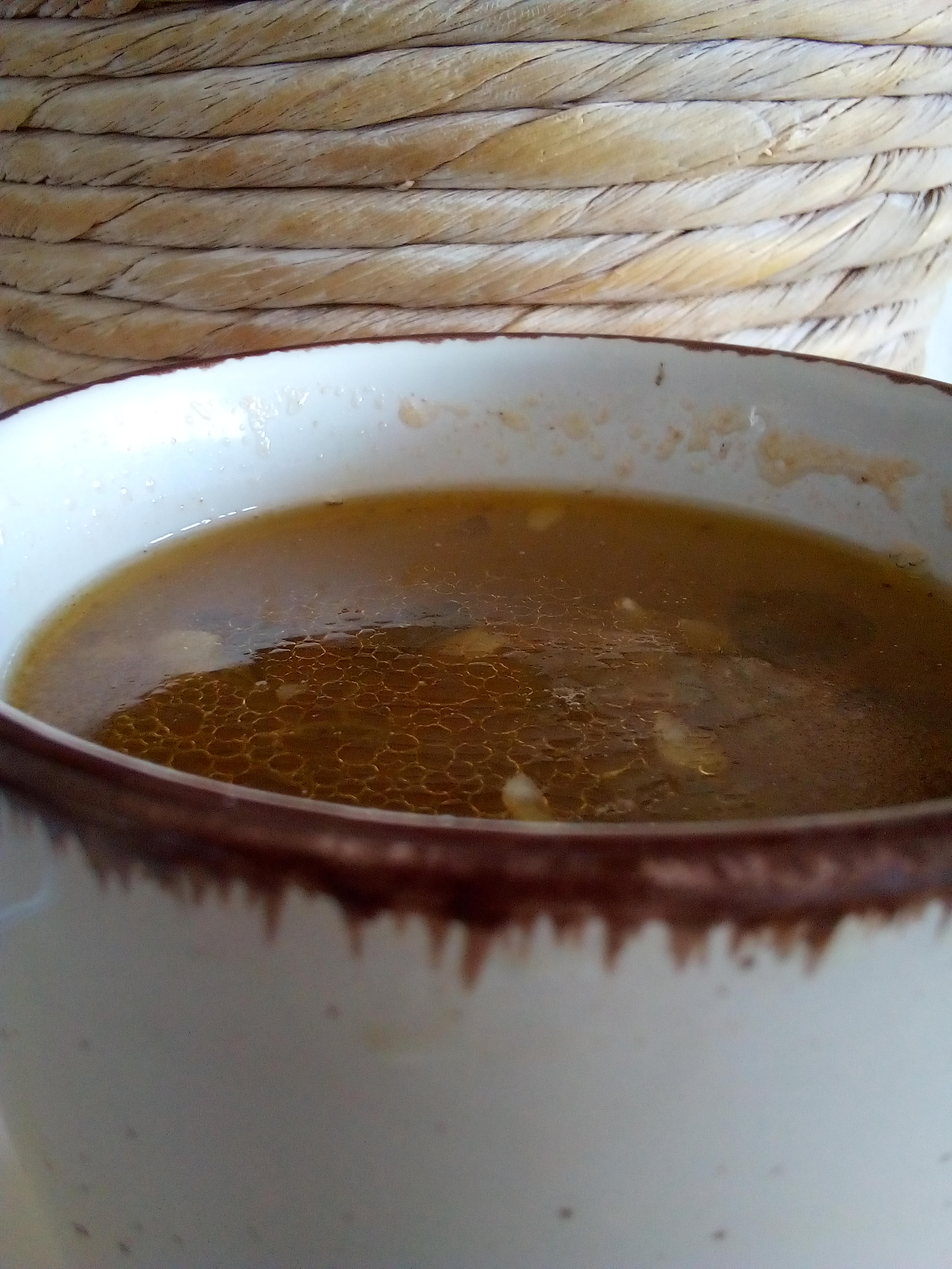 Storing homemade beef broth in jars or containers after straining to preserve flavor nutrients and quality for later homestead cooking.